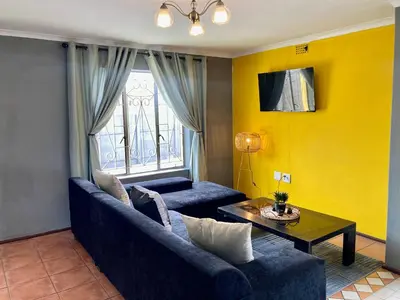 a living room with a blue couch and a table at Unit 1, TraversHub Sleeps 6 Self-Catering Group Belhar, CT in Belhar