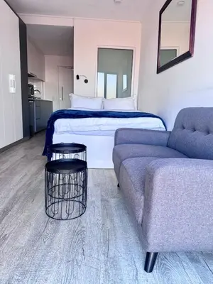 a bedroom with a bed and a couch and a bed at Modern Studio at 1 on Albert with Habour View in Cape Town