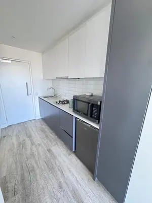 a kitchen with white cabinets and a microwave at Harbour View Modern Studio at One on Albert in Cape Town