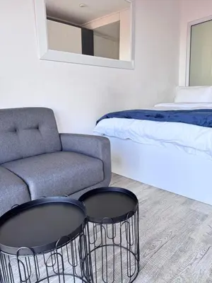 a bedroom with a couch and two chairs in front of a bed at Harbour View Modern Studio at One on Albert in Cape Town
