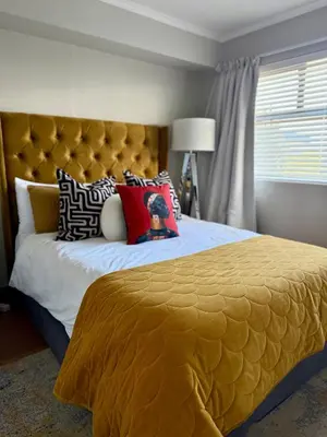 a bedroom with a large bed with a yellow bedspread at Divine Apartment Century City in Cape Town