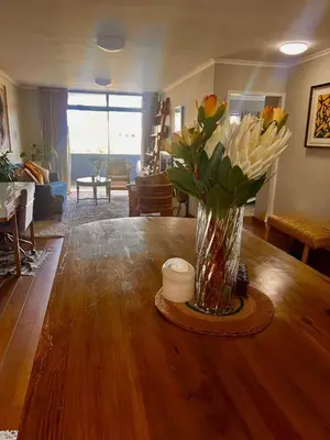 a vase of flowers sitting on top of a wooden table at Divine Apartment Century City in Cape Town