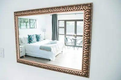 a mirror reflecting a bedroom with a bed and a table at Crayfish at Hermanus Reefs in Hermanus