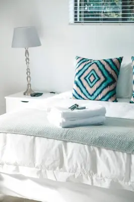 a bed with a white mattress and a lamp on it at Crayfish at Hermanus Reefs in Hermanus