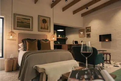 a bedroom with a bed and a table with a glass of wine at The Little Black Box in Somerset West