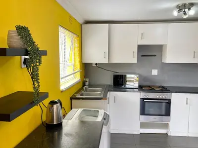 a kitchen with white cabinets and a yellow wall at Unit 2 TraversHub Sleeps 6 Self-Catering Group Belhar, CT in Belhar