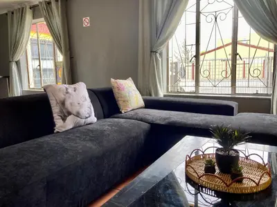 a living room with a blue couch with a teddy bear on it at Unit 2 TraversHub Sleeps 6 Self-Catering Group Belhar, CT in Belhar