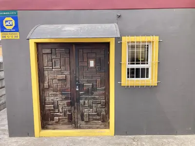a building with a wooden door and a window at Unit 2 TraversHub Sleeps 6 Self-Catering Group Belhar, CT in Belhar