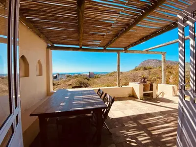 a table and chairs on a patio with a view at Cape Holly Beach House in Pringle Bay