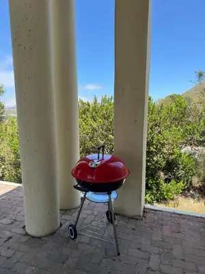a red bbq grill sitting on a porch at Sea and Vlei on Disa in Bettyʼs Bay