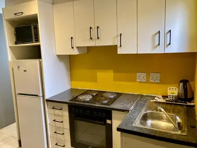 a kitchen with white cabinets and a sink and a refrigerator at Unit 3 TraversHub Sleeps 6 Self-Catering Group Belhar, CT in Belhar