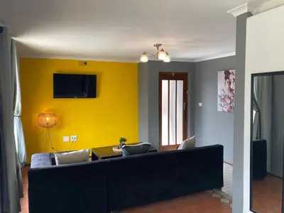a living room with a couch and a yellow wall at Unit 3 TraversHub Sleeps 6 Self-Catering Group Belhar, CT in Belhar