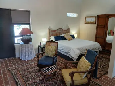 a bedroom with a bed and chairs and a table at Chasselas Studio in Somerset West