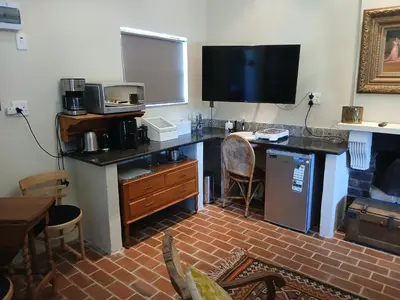 a room with a desk with a television and a counter with a microwave at Chasselas Studio in Somerset West