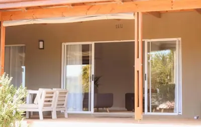a screened in porch with two chairs and a table at Rissie's 3 Bedroom Apartment in Gordonʼs Bay