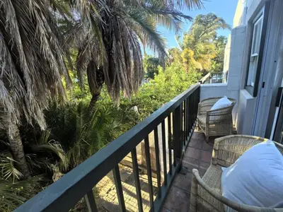 a balcony with chairs and palm trees on a house at Offbeat off Dorp in Stellenbosch