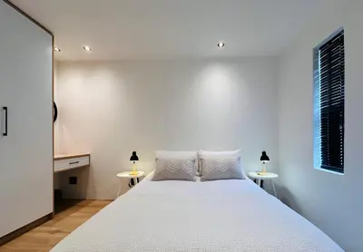 a bedroom with a white bed and two tables at Modern Scandinavian Luxury Apartment in Hermanus