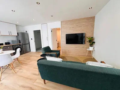 a living room with a green couch and a flat screen tv at Modern Scandinavian Luxury Apartment in Hermanus