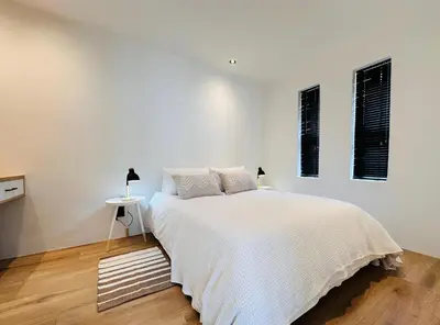 a white bedroom with a bed and two windows at Modern Scandinavian Luxury Apartment in Hermanus