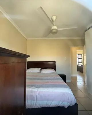 a bedroom with a bed with a ceiling fan at Holiday Home in Cape Town