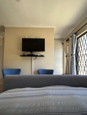 a bedroom with a bed with a flat screen tv on the wall at Holiday Home in Cape Town
