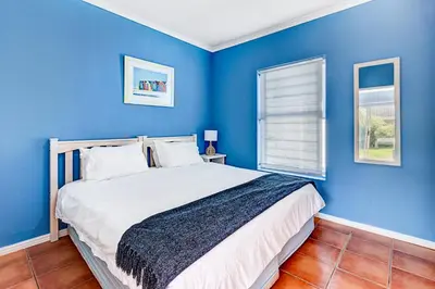 a blue bedroom with a large bed in a room at Sea Breeze Kite Dreams 3 in Cape Town