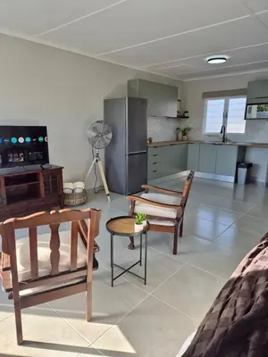 a living room with chairs and a kitchen at Sand & Sea Studio Hermanus in Hermanus
