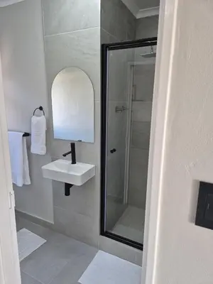 a bathroom with a sink and a mirror and a shower at Sand & Sea Studio Hermanus in Hermanus