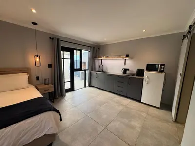a bedroom with a bed and a kitchen with a refrigerator at One-Bedroom apartment in Somerset West in Helderberg