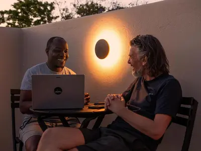 two men sitting at a table with a laptop at Guesthouse Ubuntu - Stellenbosch in Stellenbosch