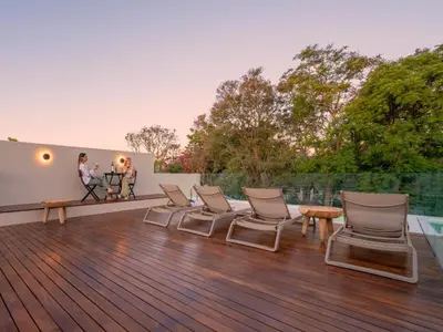 a deck with chairs and a table and two people at Guesthouse Ubuntu - Stellenbosch in Stellenbosch