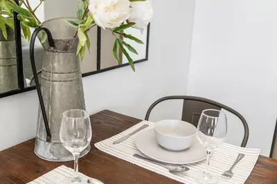 a wooden table with a vase and a plate and glasses at Beach Break 17 in Cape Town