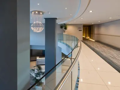 a glass staircase in a building with a chandelier at Krystal Beach Hotel in Gordonʼs Bay