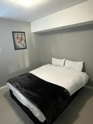 a bedroom with a large white bed with a black blanket at Minimalist 2 bed 1 full bathroom in Cape Town