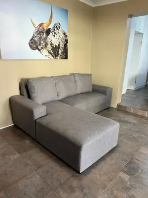 a couch in a living room with a picture of a cow at Kabana Guest House Morgenzicht in Windsor Park
