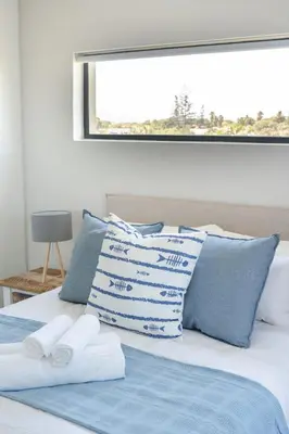 a bed with blue and white pillows on it at Manchester Heights Deluxe Apartments in Cape Town