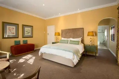a bedroom with a large bed and yellow walls at Milkwood Lodge in Hermanus