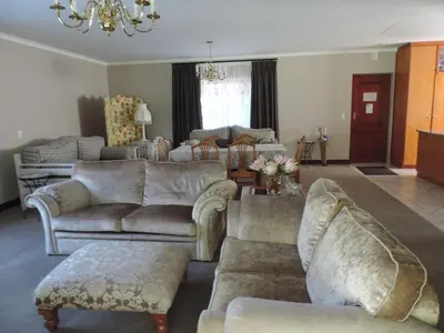 a living room with couches and chairs and a chandelier at Milkwood Lodge in Hermanus