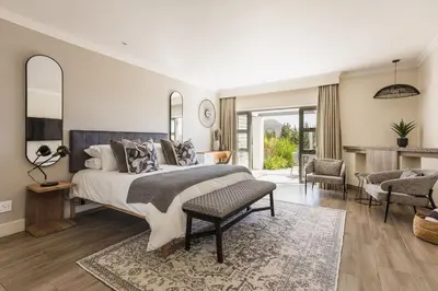 a bedroom with a large bed and a living room at Winelands Luxury Unit in Stellenbosch