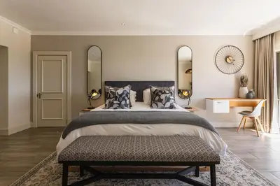 a bedroom with a large bed with two mirrors at Winelands Luxury Unit in Stellenbosch