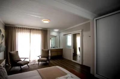 a bedroom with a bed and two chairs and a window at Tide & Together in Hermanus