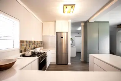 a kitchen with a stainless steel refrigerator and white cabinets at Tide & Together in Hermanus