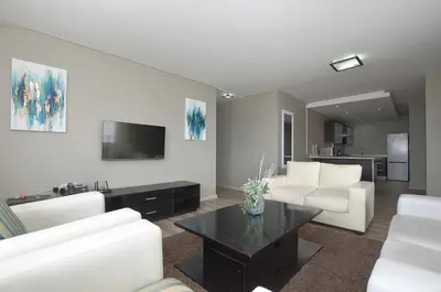 a living room with a couch and a table at Luxury Beachside Apartment in Aquarius in Cape Town