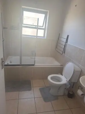 a bathroom with a toilet and a tub and a sink at Stepney Apartment in Cape Town