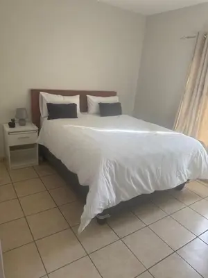 a bedroom with a large bed with white sheets and pillows at Stepney Apartment in Cape Town