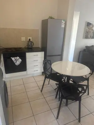 a small kitchen with a table and a refrigerator at Stepney Apartment in Cape Town