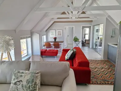 a living room with a red couch and a kitchen at Salted in Cape Town