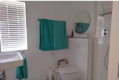 a bathroom with a green shower curtain and a mirror at Luxury Beach Front Apartment in Strand