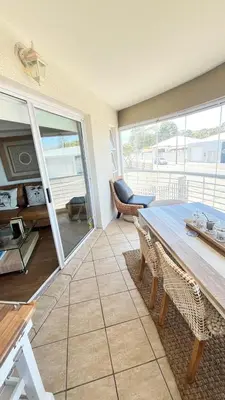 a living room with a table and chairs and a balcony at Luxury Beach Front Apartment in Strand