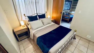 a bedroom with a bed with blue and white pillows at Casa Kari in Brackenfell